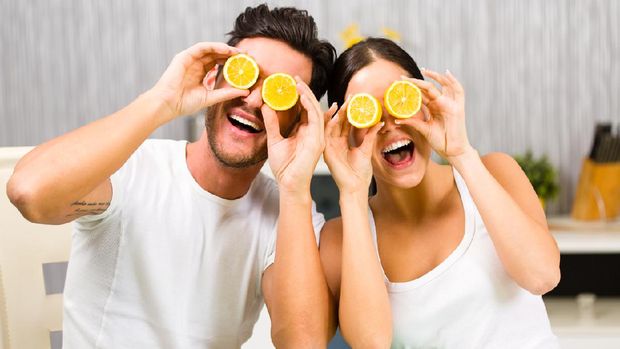 Young man and woman having fun with lemon while having a breakfast.
