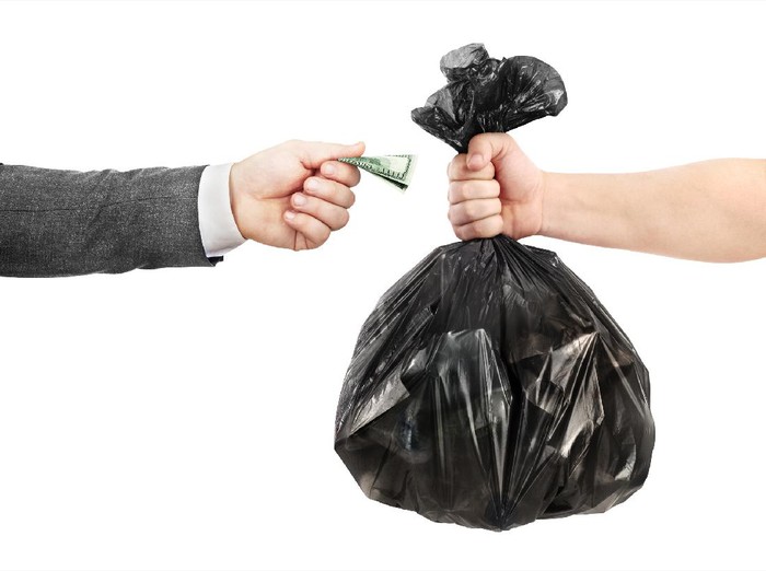 The concept of recycling. A male hand in a jacket transfers money to the other hand in exchange for a garbage bag.