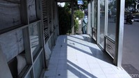 Jendela yang bolong hanya ditutupi dengan spanduk. Selain itu lantai halte juga kotor.