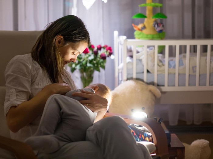 menyusui malam hari Young beautiful mother, breastfeeding her newborn baby boy at night, dim light. Mom breastfeeding infant