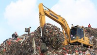 Alat berat terlihat menggali gunungan sampah.
