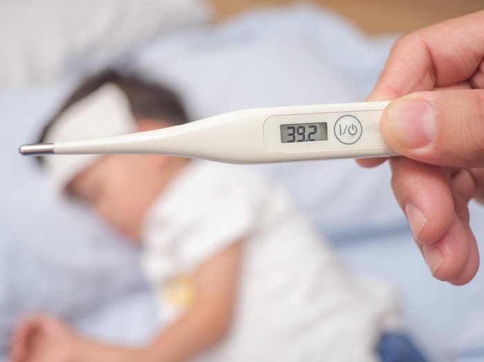 Fever, Close-up medical thermometer, Parent / Father measuring temperature of his ill kid, Asian 3 - 4 years old toddler boy gets high fever lying on bed with cold compress on forehead to cool a fever
