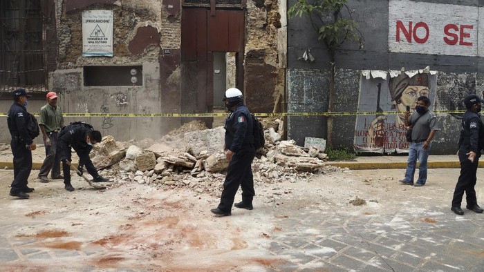 A policeman removes rubble from a building damaged by an earthquake in Oaxaca, Mexico, Tuesday, June 23, 2020. The earthquake was centered near the resort of Huatulco, in the southern state of Oaxaca. (AP Photo/Luis Alberto Cruz Hernandez)