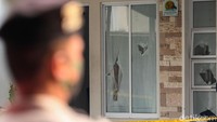 Seorang polisi berjaga di depan rumah yang tampak rusak dibagian jendelanya usai dirusak oleh kelompok John Kei.