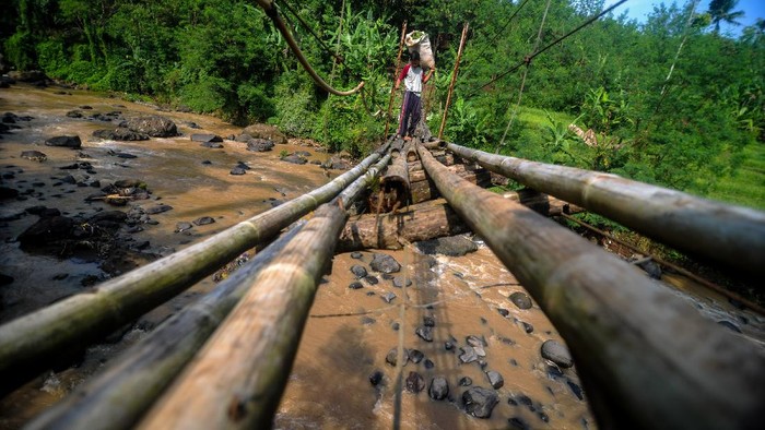 Seorang buruh tani menyeberangi jembatan gantung yang rapuh di Desa Kertamukti, Kabupaten Bandung Barat, Jawa Barat, Rabu (24/6/2020). Menurut keterangan warga setempat, jembatan yang telah ada pada 1980-an dan menjadi penghubung antara Desa Kertamukti dan Desa Cipatat tersebut saat ini kondisinya rusak parah dan  warga berharap adanya perbaikan dari pemerintah setempat. ANTARA FOTO/Raisan Al Farisi/aww.