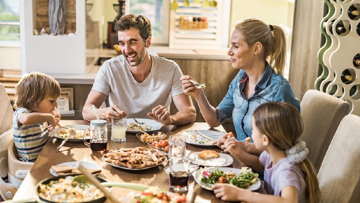 Happy family enjoying lunch while kids playing.