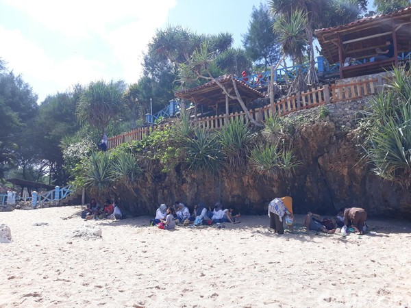 Wisatawan di Pantai Kukup berjejer di bawah tebing. Mereka menjaga jarak antara kelompok yang satu dengan lainnya. Wisatawan di Pantai Kukup berjejer di bawah tebing. Mereka menjaga jarak antara kelompok yang satu dengan lainnya.