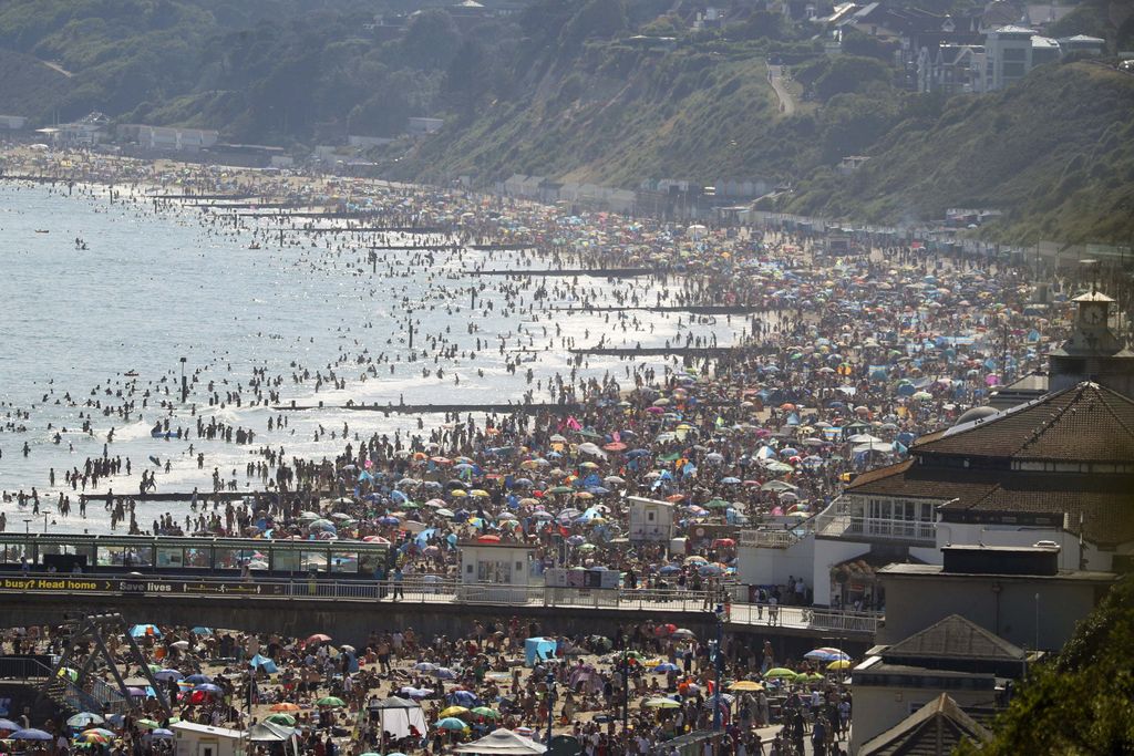 On Britain's hottest day of the year so far with temperatures reaching 32.6 degrees at Heathrow, people relax in the sea and on Brighton Beach in Brighton, England, Wednesday, June 24, 2020. The British government announced Tuesday that from July 4 social-distancing rules will be relaxed. People will be advised to stay at least 1 meter (3 feet) apart from others, rather than requiring 2 meters -- as long as they take other measures to reduce transmission of the virus, such as wearing a mask in enclosed spaces. (AP Photo/Matt Dunham)