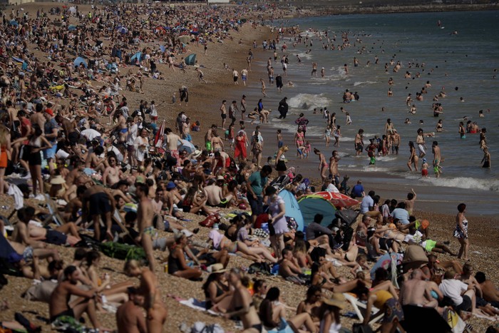 On Britains hottest day of the year so far with temperatures reaching 32.6 degrees at Heathrow, people relax in the sea and on Brighton Beach in Brighton, England, Wednesday, June 24, 2020. The British government announced Tuesday that from July 4 social-distancing rules will be relaxed. People will be advised to stay at least 1 meter (3 feet) apart from others, rather than requiring 2 meters -- as long as they take other measures to reduce transmission of the virus, such as wearing a mask in enclosed spaces. (AP Photo/Matt Dunham)