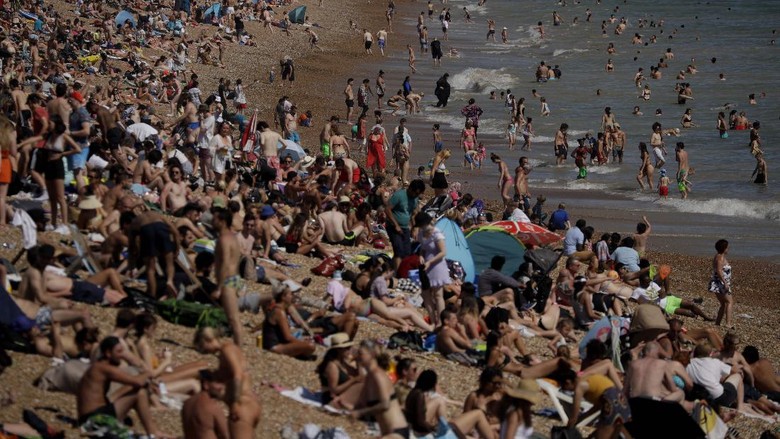 Potret Warga Inggris Menyemut di Pantai Bournemouth On Britains hottest day of the year so far with temperatures reaching 32.6 degrees at Heathrow, people relax in the sea and on Brighton Beach in Brighton, England, Wednesday, June 24, 2020. The British government announced Tuesday that from July 4 social-distancing rules will be relaxed. People will be advised to stay at least 1 meter (3 feet) apart from others, rather than requiring 2 meters -- as long as they take other measures to reduce transmission of the virus, such as wearing a mask in enclosed spaces. (AP Photo/Matt Dunham)