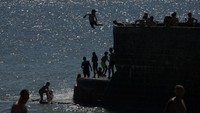 Mereka menikmati suasana pantai saat cuaca panas menyengat.