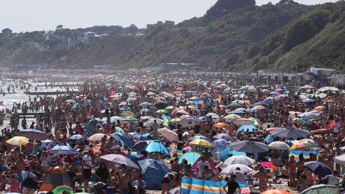 On Britains hottest day of the year so far with temperatures reaching 32.6 degrees at Heathrow, people relax in the sea and on Brighton Beach in Brighton, England, Wednesday, June 24, 2020. The British government announced Tuesday that from July 4 social-distancing rules will be relaxed. People will be advised to stay at least 1 meter (3 feet) apart from others, rather than requiring 2 meters -- as long as they take other measures to reduce transmission of the virus, such as wearing a mask in enclosed spaces. (AP Photo/Matt Dunham)