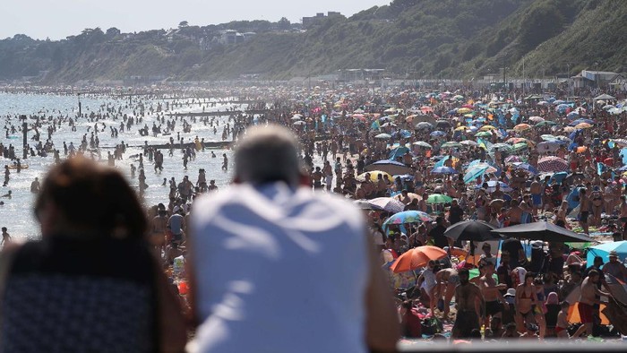 Potret Warga Inggris Menyemut di Pantai Bournemouth On Britain's hottest day of the year so far with temperatures reaching 32.6 degrees at Heathrow, people relax in the sea and on Brighton Beach in Brighton, England, Wednesday, June 24, 2020. The British government announced Tuesday that from July 4 social-distancing rules will be relaxed. People will be advised to stay at least 1 meter (3 feet) apart from others, rather than requiring 2 meters -- as long as they take other measures to reduce transmission of the virus, such as wearing a mask in enclosed spaces. (AP Photo/Matt Dunham)