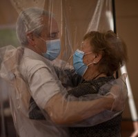 Keharuan terjadi di Ballesol Puig i Fabra, sebuah panti jompo di Barcelona, Spanyol, pada Senin (22/6/2020). Di hari itu, para penghuni akhirnya mendapatkan kesempatan untuk bertemu keluarga mereka setelah beberapa bulan terpisah karena pandemi COVID-19. Mereka juga boleh melakukan kontak fisik, seperti berpelukan, tapi harus dengan menggunakan partisi plastik demi melindungi sesama. (Foto: AP/Emilio Morenatti)