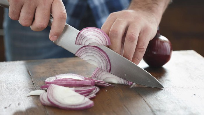 Close up male hands chopped fresh red onion on wooden table