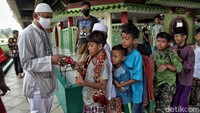 Anak-anak yang tidak memakai masker antre untuk menerima masker.