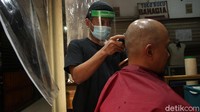 Tampak tukang cukur tengah melayani konsumennya.