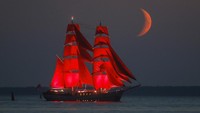 Terdapat kapal layar dengan warna merah menyala ditambah latar belakang bulan sabit berwarna senada yang sangat mempesona.