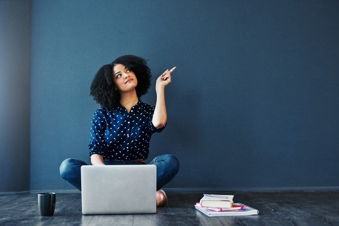 Ilustrasi kuliah online Studio shot of an attractive young woman looking thoughtful while using a laptop against a blue background