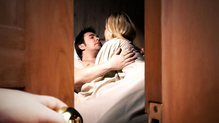 Ilustrasi pernikahan bahagia Couple lying in bed while someone is watching in front of the door