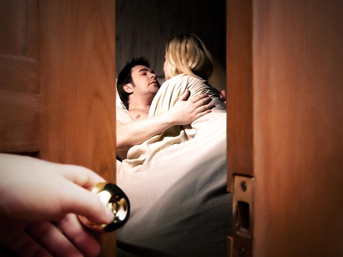 Ilustrasi pernikahan bahagia Couple lying in bed while someone is watching in front of the door
