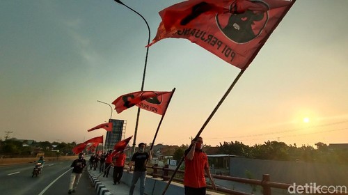 Kader PDIP Kudus memasang bendera partai di Jembatan Tanggulangin, pintu masuk Kabupaten Kudus, Sabtu (27/6/2020).