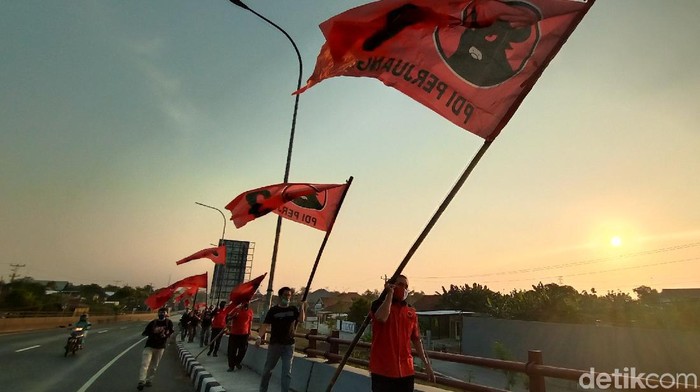 Kader PDIP Kudus memasang bendera partai di Jembatan Tanggulangin, pintu masuk Kabupaten Kudus, Sabtu (27/6/2020).