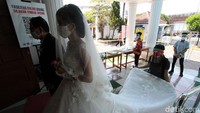 Pengantin yang mengenakan masker berjalan memasuki gereja seusai cek suhu tubuh.