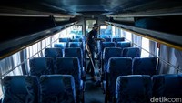 Seorang petugas sedang membersihkan bagian dalam bus yang terparkir di kawasan Terminal Jatijajar, Depok, Jawa Barat.