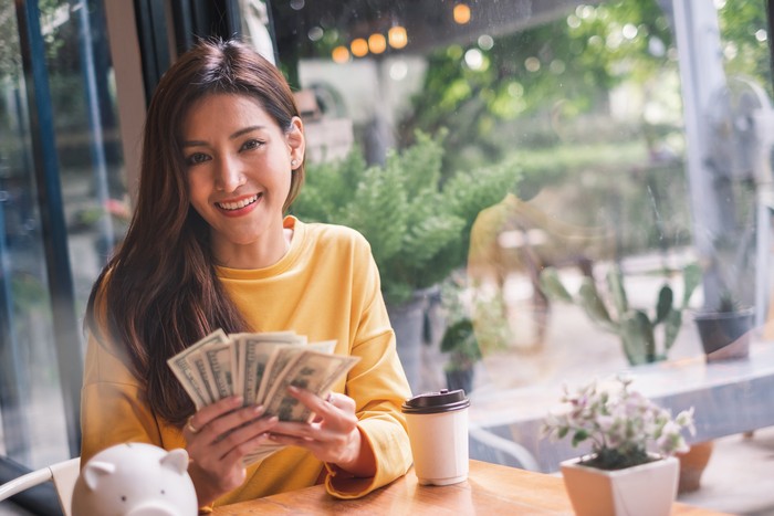 zodiak happy Asian woman hand holding smart phone and banknotes ,make money online concept