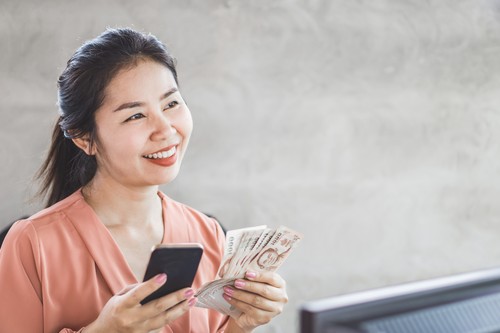 happy Asian woman hand holding smart phone and banknotes ,make money online concept