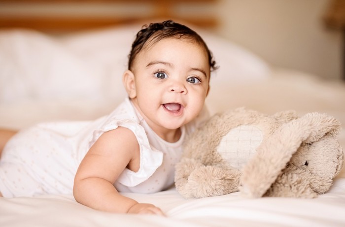 1160269739 Shot of a cute baby girl on bed with a soft toy