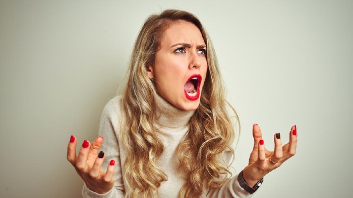Beautiful woman wearing winter turtleneck sweater over isolated white background crazy and mad shouting and yelling with aggressive expression and arms raised. Frustration concept.
