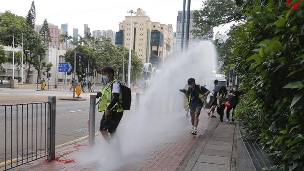 Journalists run as police fire water cannons during a march against the new national security law on the anniversary of Hong Kong's handover to China from Britain in Hong Kong, Wednesday, July. 1, 2020. Hong Kong marked the 23rd anniversary of its handover to China in 1997, and just one day after China enacted a national security law that cracks down on protests in the territory. (AP Photo/Kin Cheung)