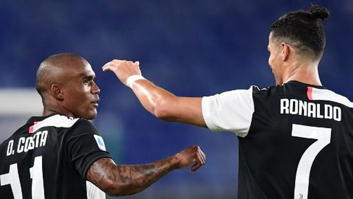 Juventus Brazilian forward Douglas Costa (L) celebrates with Juventus Portuguese forward Cristiano Ronaldo after scoring during the Italian Serie A football match Genoa vs Juventus played on June 30, 2020 behind closed doors at the Luigi-Ferraris stadium in Genoa, as the country eases its lockdown aimed at curbing the spread of the COVID-19 infection, caused by the novel coronavirus. (Photo by Miguel MEDINA / AFP)