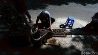 Sambil menunggu pembeli, seorang membersihkan barang dagangannya.