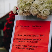 Sebelum memasuki area pelaminan, terpasang papan pengumuman yang memberitahukan SOP kondangan. Dalam SOP tersebut tertulis tamu undangan hanya diizinkan berhenti selama satu menit untuk memberi ucapan selamat pada kedua mempelai. Para tamu juga tidak diizinkan turun dari kendaraannya. Foto: Dok. Zenuz Production