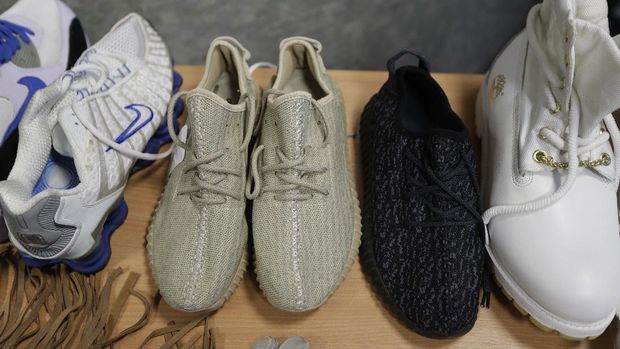 In this Wednesday. Feb. 22, 2017 photo, seized counterfeit footwear, including copies of Adidas and Kanye West Yeezy Boost trainers, centre, are displayed to be photographed at UK Border Force offices in London.  In the past five years, the Border Force, the policing command under Britain’s Home Office charged with immigration and customs controls, has seized thousands of consignments at Heathrow alone, valued at around £100 million ($125 million).  (AP Photo/Matt Dunham)