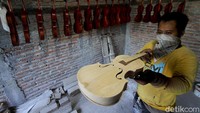 Perajin mencoba biola buatanya dirumahnya sebelum dikirim kepada pembeli di Pondok, Krangkungan, Sukoharjo, Jawa Tengah (1/7/2020).