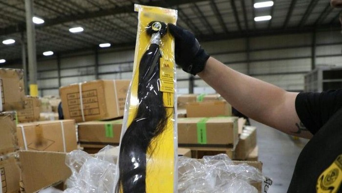 A US Customs and Border Protection officer at the Port of New York/Newark inspects a shipment of hair pieces and accessories from China suspected to have been made with forced or prison labor (AFP Photo/Handout)
