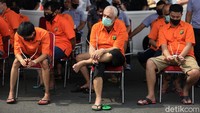 Para tersangka dihadirkan dengan memakai baju tahanan.