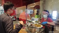 Lalu di area restoran, setiap tamu dilayani karyawan yang telah dilengkapi masker, face shield, dan sarung tangan. Selain itu antara karyawan dengan tamu juga ada pembatas mika untuk meminalisir kontak fisik antara keduanya. Di meja dan kursi juga diberi tanda jaga jarak.  (Foto: Putu Intan/detikcom)