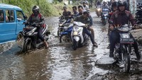 Pengendara melintasi jalan yang rusak dan digenangi air di Jalan Raya Bojong Gede-Citayam, Cibinong, Kabupaten Bogor, Jawa Barat, Jumat (3/7/2020).