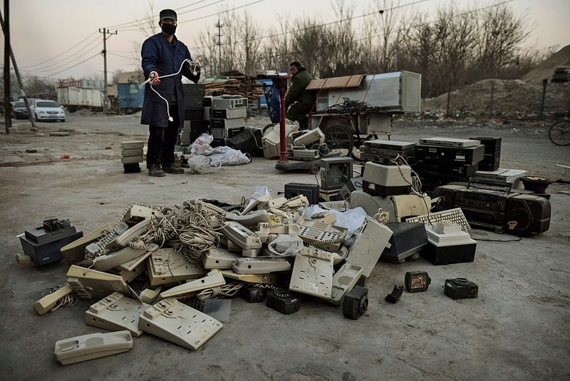 BEIJING, CHINA - DECEMBER 11: A Chinese laborer gathers telephones and other electronic items to be recycled in the Dong Xiao Kou village on December 11, 2014 in Beijing, China. The village, is made up mostly of families of poor migrant workers that have come from surrounding provinces and are some of the tens of thousands of scrap peddlars surviving on recycling goods collected in China's capital. China is the world's biggest generator of solid waste and as the country's population and economy continue to grow the peddlars are integral to the waste and recycling management system in major cities. (Photo by Kevin Frayer/Getty Images)
