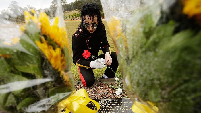 Potret 11 Tahun Kematian Michael Jackson SYDNEY, AUSTRALIA - JUNE 26: Michael Jackson impersonator Jason Jackson lays a carnation at the memorial plaque during a memorial service commemorating the first anniversary of his death at Forest Lawn Memorial Park on June 26, 2010 in Sydney, Australia. Fans across the globe marked the passing of Jackson in a simultaneous 'World Cry' tribute hosted in various cities including New York, London and Paris. (Photo by Brendon Thorne/Getty Images)