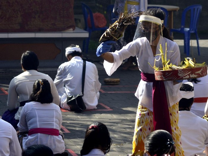 Umat Hindu mengenakan alat pelindung diri saat mengikuti rangkaian persembahyangan perayaan Hari Saraswati di Badung, Bali, Sabtu (4/7/2020). Perayaan Hari Raya Saraswati yang diperingati umat Hindu sebagai hari turunnya ilmu pengetahuan yang diselenggarakan di sebuah sekolah tersebut dilakukan dengan menerapkan protokol kesehatan secara ketat dan hanya diikuti oleh perwakilan guru, pegawai dan siswa dengan jumlah 25 orang sebagai upaya pencegahan COVID-19. ANTARA FOTO/Fikri Yusuf/hp.