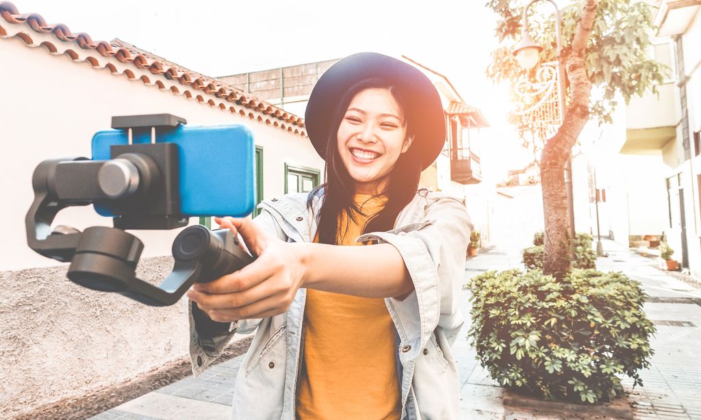 Ilustrasi YouTuber Happy asian woman vlogging with gimbal tripod and smartphone - Influencer chinese girl having fun with new trend technology - Millennial generation activity job, youth and tech concept - Focus on face