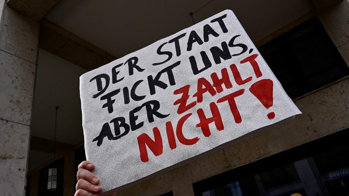 A sex worker holds a placard reading the state fucks us but does not pay during a protest to demand the reopening of brothels amid the new coronavirus pandemic on July 3, 2020 near the Bundesrat (upper house of parliament) in Berlin. (Photo by John MACDOUGALL / AFP)