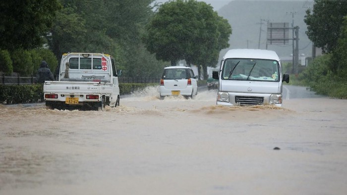 Vehicles pass through a flooded road caused by heavy rain in Yatsushiro, Kumamoto prefecture on July 4, 2020. - Some 75,000 people were ordered to evacuate in western Japan on July 4 as record heavy rain triggered floods and landslides, local media and officials said. The nations weather agency issued the highest level of heavy rain warnings to Kumamoto and Kagoshima on Kyushu island. (Photo by STR / JIJI PRESS / AFP) / Japan OUT