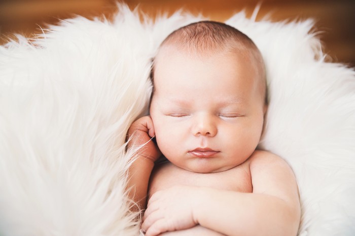 853843712 Sleeping newborn baby on white blanket. Beautiful portrait of little child girl 7 days, one week old.